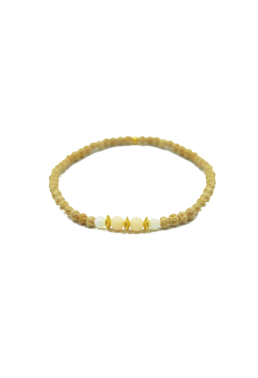 A mesmerizing Uluwatu Moon Bracelet, featuring 2mm rudrani seeds, pink coral, and moonstone beads, adorned with a stunning pearl pendant and 22k gold accents. Inspired by the full-moon casting a radiant runway onto the waves of Uluwatu Beach, this celestial accessory evokes beachside meditations and invites you to trust in the magnificence of the cosmos.