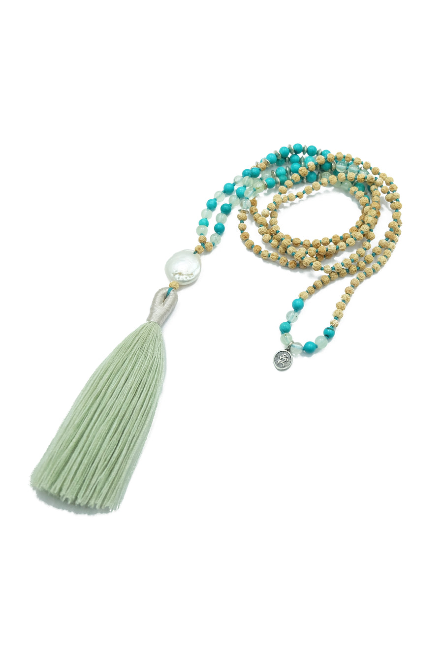 A captivating mala necklace named 'Lanikai Sunrise' with serene ocean-inspired colors. The mala features beautiful 4mm prehnite, turquoise gemstones, and rudrani seeds, complemented by elegant sterling silver accents. At its heart, a shimmering freshwater pearl pendant adds a touch of sophistication. Experience the bliss of floating weightless in heavenly waves under the tropical sun with this enchanting mala.