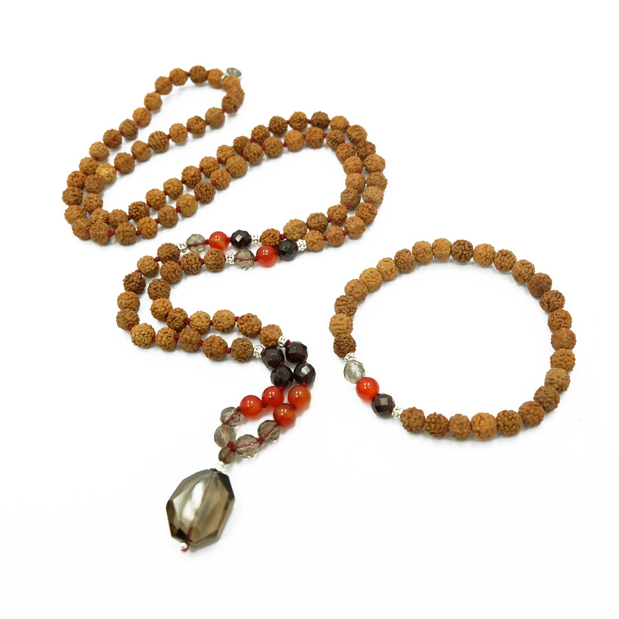 An exquisite mala with 108 beads, 7mm Rudraksha seeds, Carnelian, Garnet, Smokey Quartz gemstones, sterling silver accents, and a captivating Smokey Quartz pendant. This mala exudes a harmonious blend of beauty, grounding energy, and elegance.